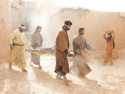 Carrying paralyzed man to Jesus